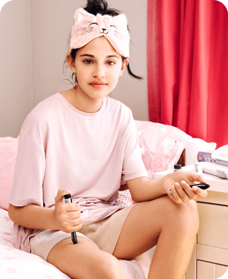 Tween girl sitting on a bed using an injection pen
